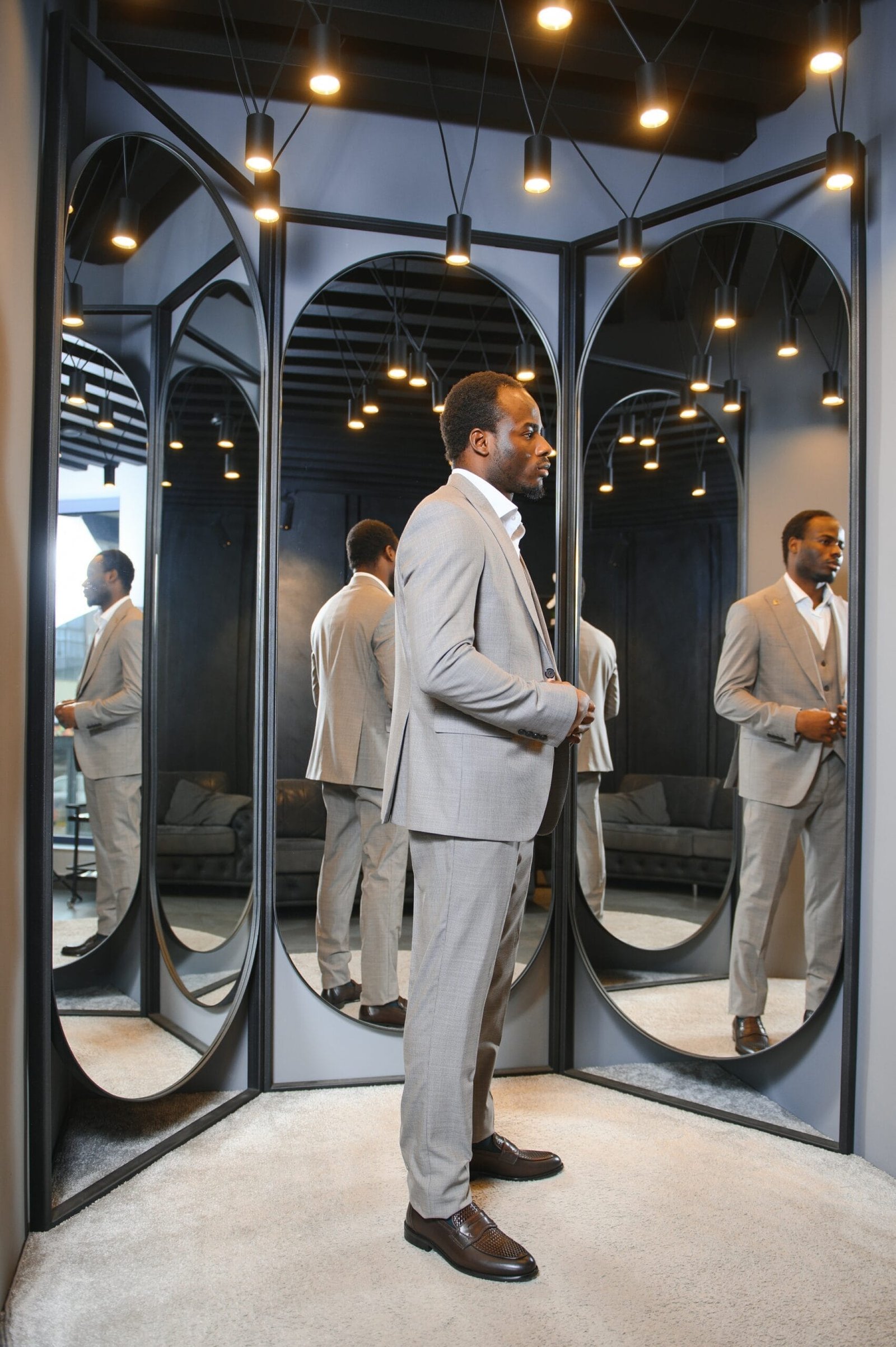 African Businessman in classic suit against row of suits in shop.