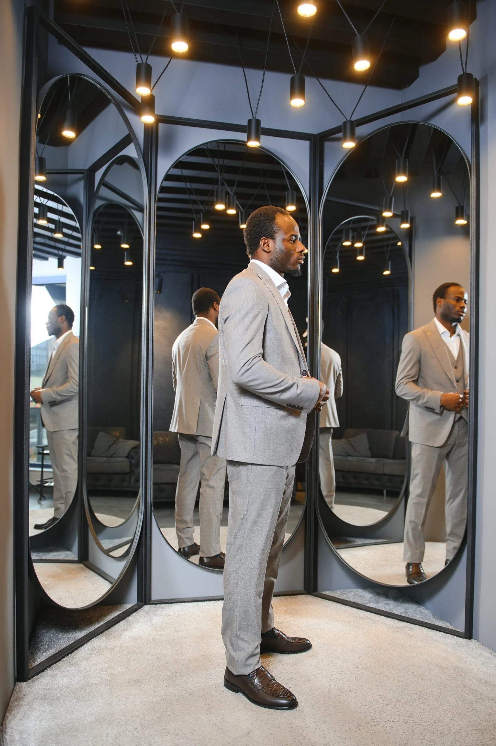 African Businessman in classic suit against row of suits in shop.